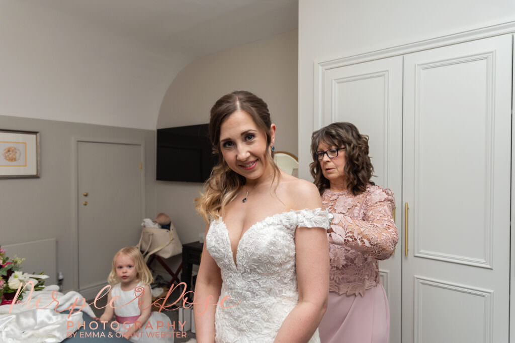 Photo of mother of the bride helping her daughter get into her wedding dress on her wedding day in Milton Keynes