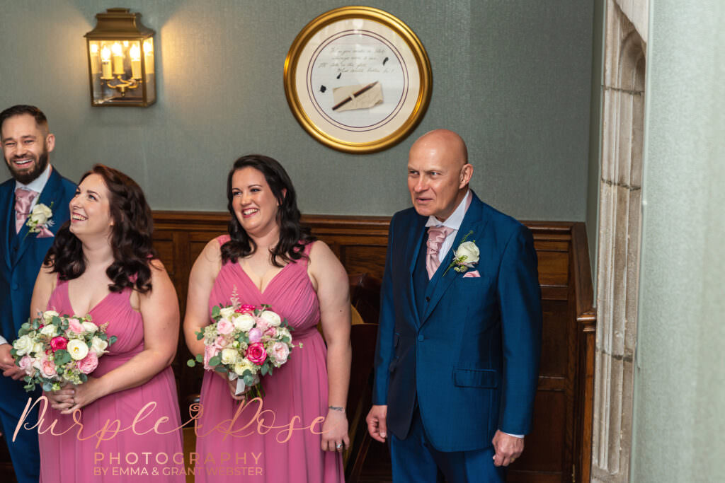 Photo of father of the bride and bridesmaids seeing the bride in her wedding dress for the first time on her wedding day in Milton Keynes