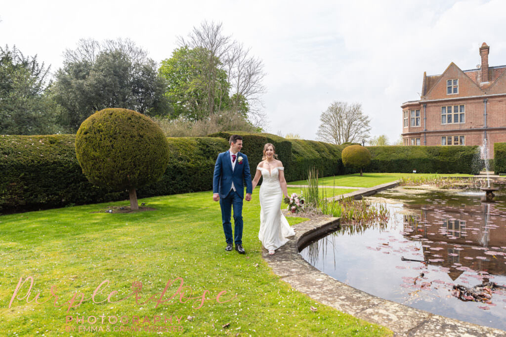 Photo of bride and groom walking around a pond on their wedding day in Milton Keynes