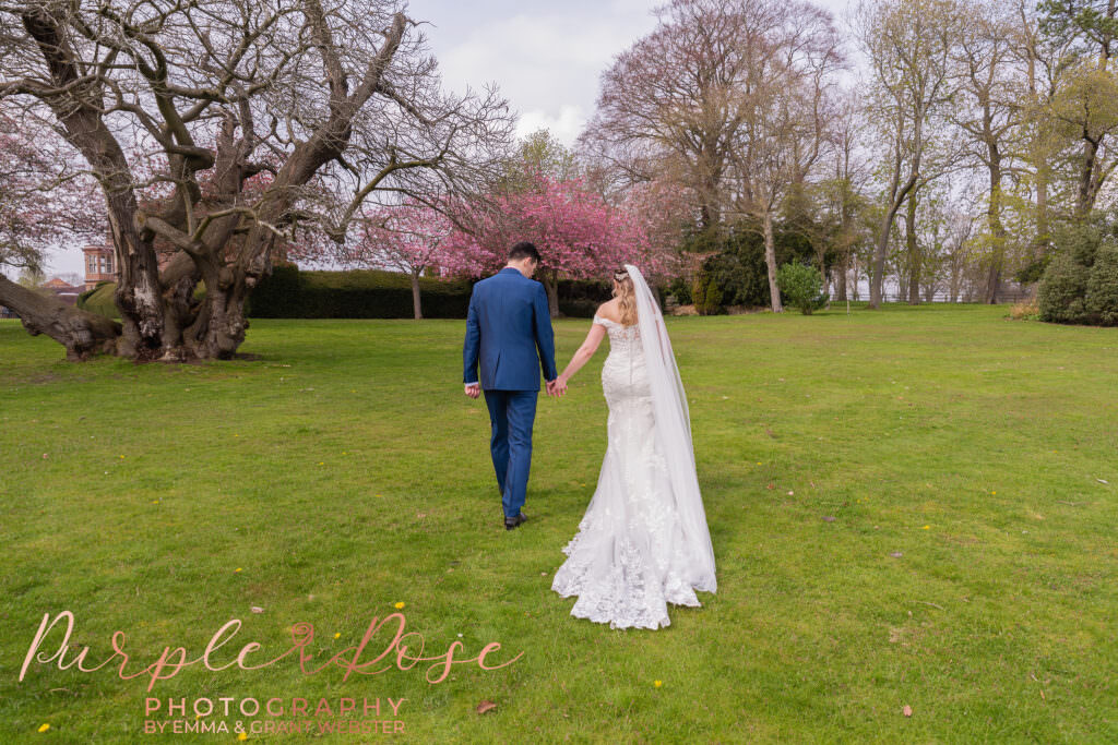 Photo of bride and groom wlaking hand in hand to their wedding venue in Milton Keynes