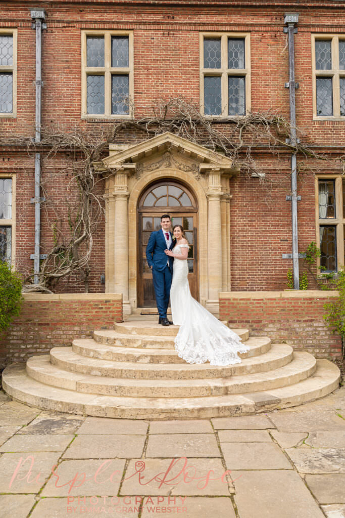 Photo of bride and groom stood on the steps of their wedding venue in Milton Keynes