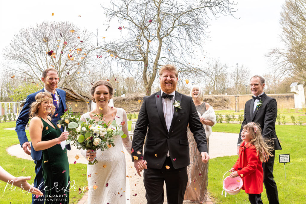 Bride and groom laughing as confetti is thrown around them in a wedding photo in Milton Keynes