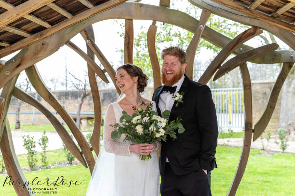 Bride and groom laughing under a gazebo after their wedding at Milton Keynes Registry Office