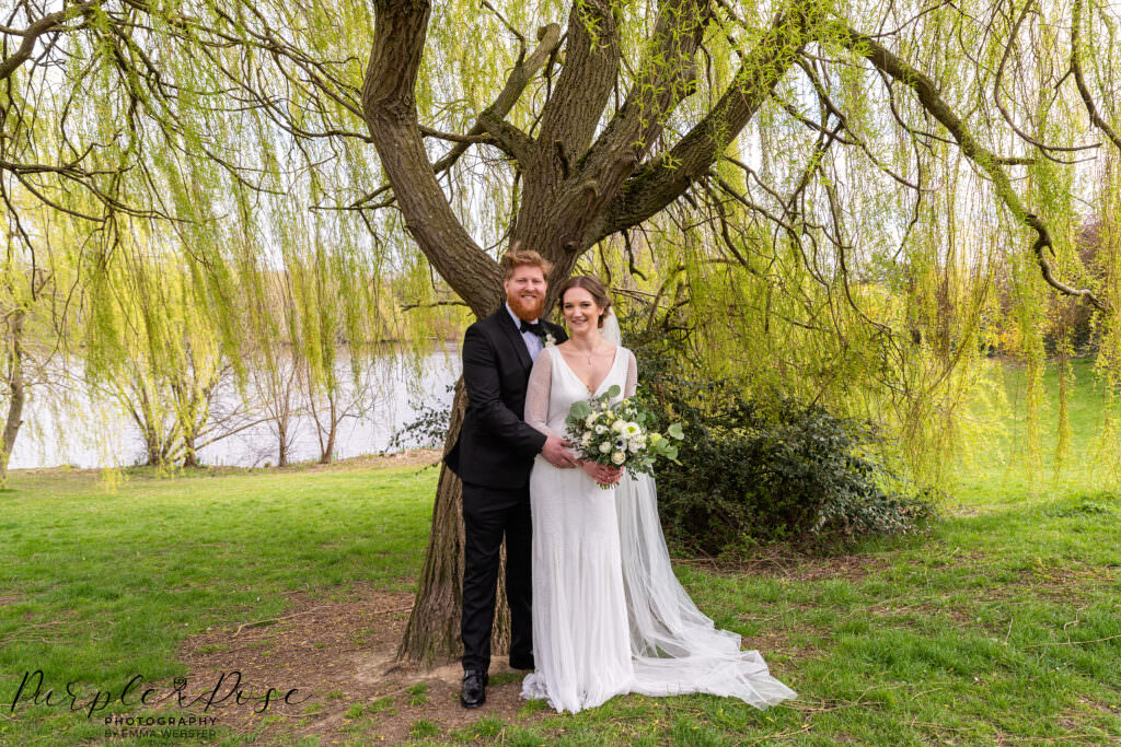 Bride and groom stood under a willow tree