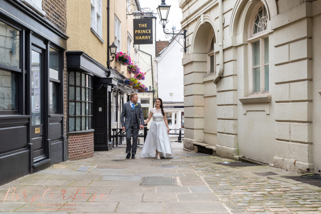 Bride and groom walking hand in hand down a cobbled street on their wedding day in Milton Keynes