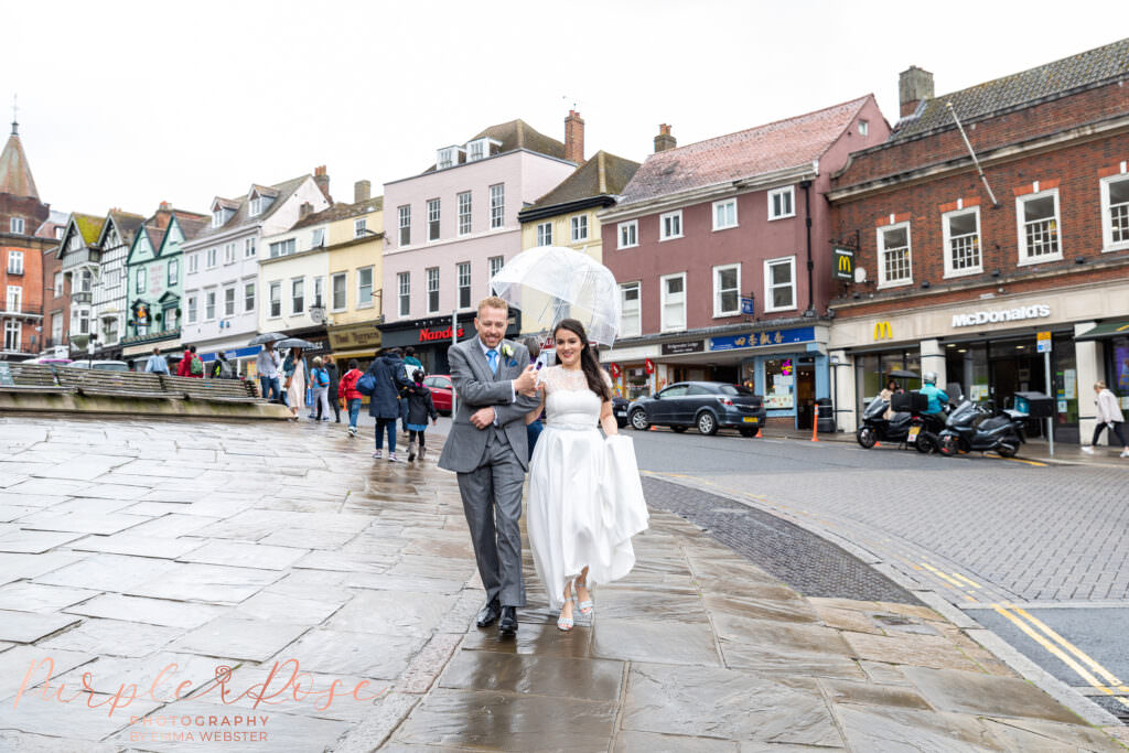 Photograph of a bride and groom sheltering under an umbrella on their wedding day in Milton Keynes
