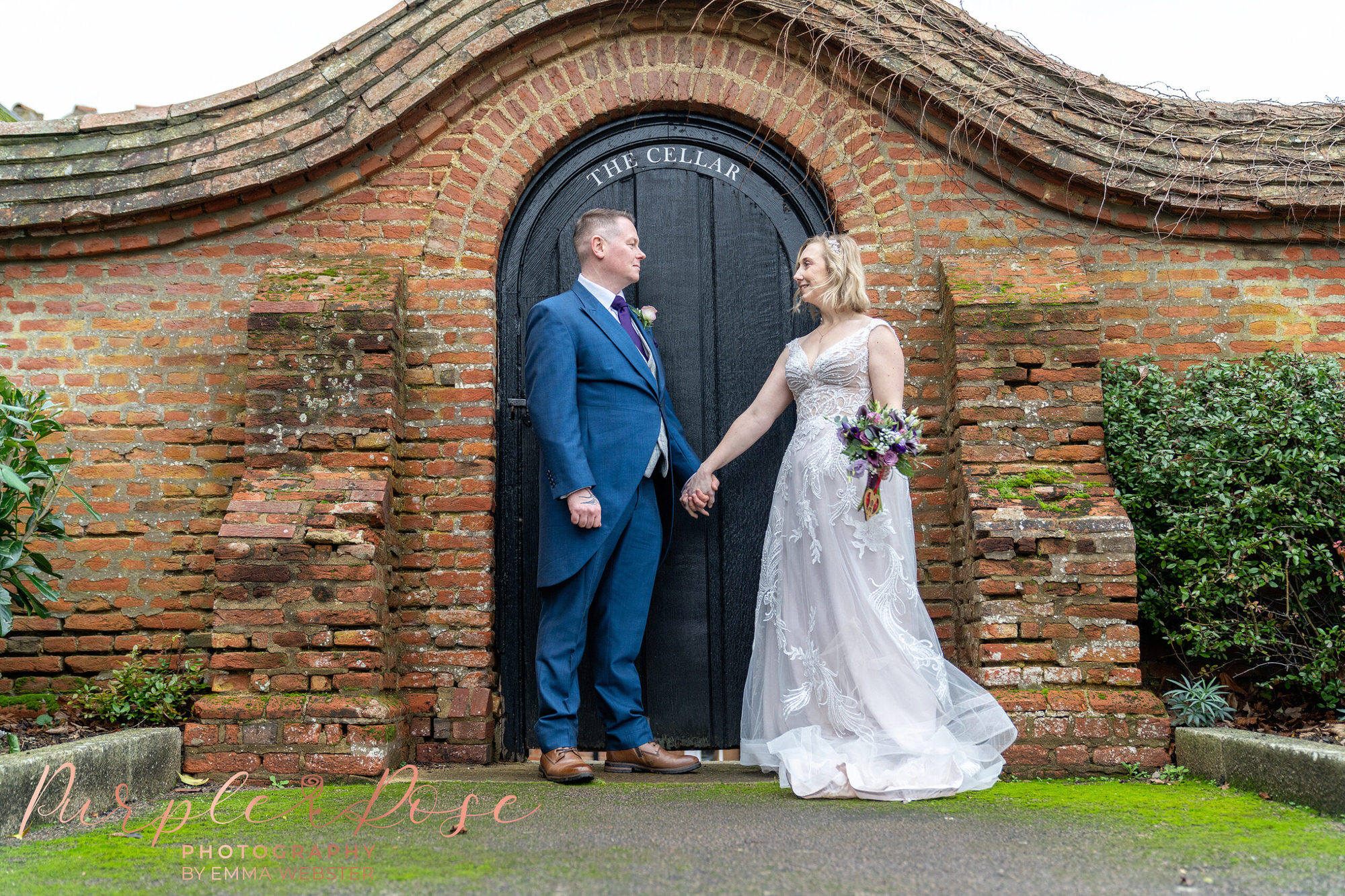 Bride and groom holding hands in front of a gate