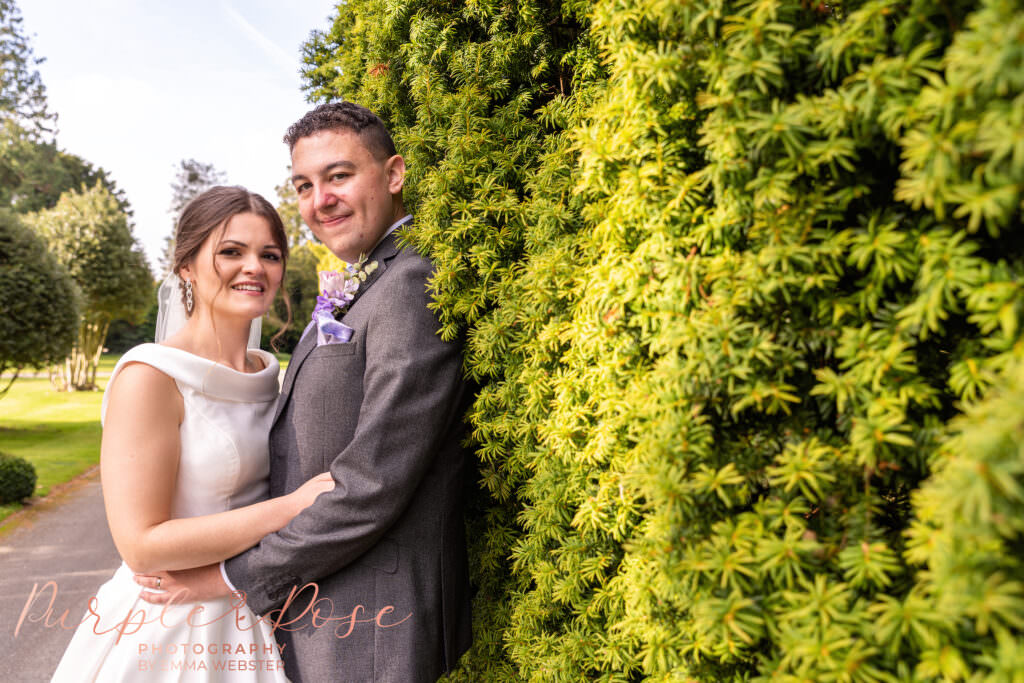 Bride and groom on a hedge lined path