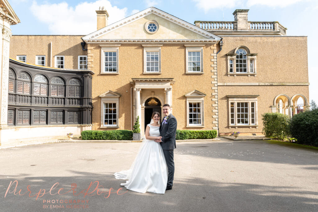 Bride and groom stood in front of their wedding venue Bourton Hall