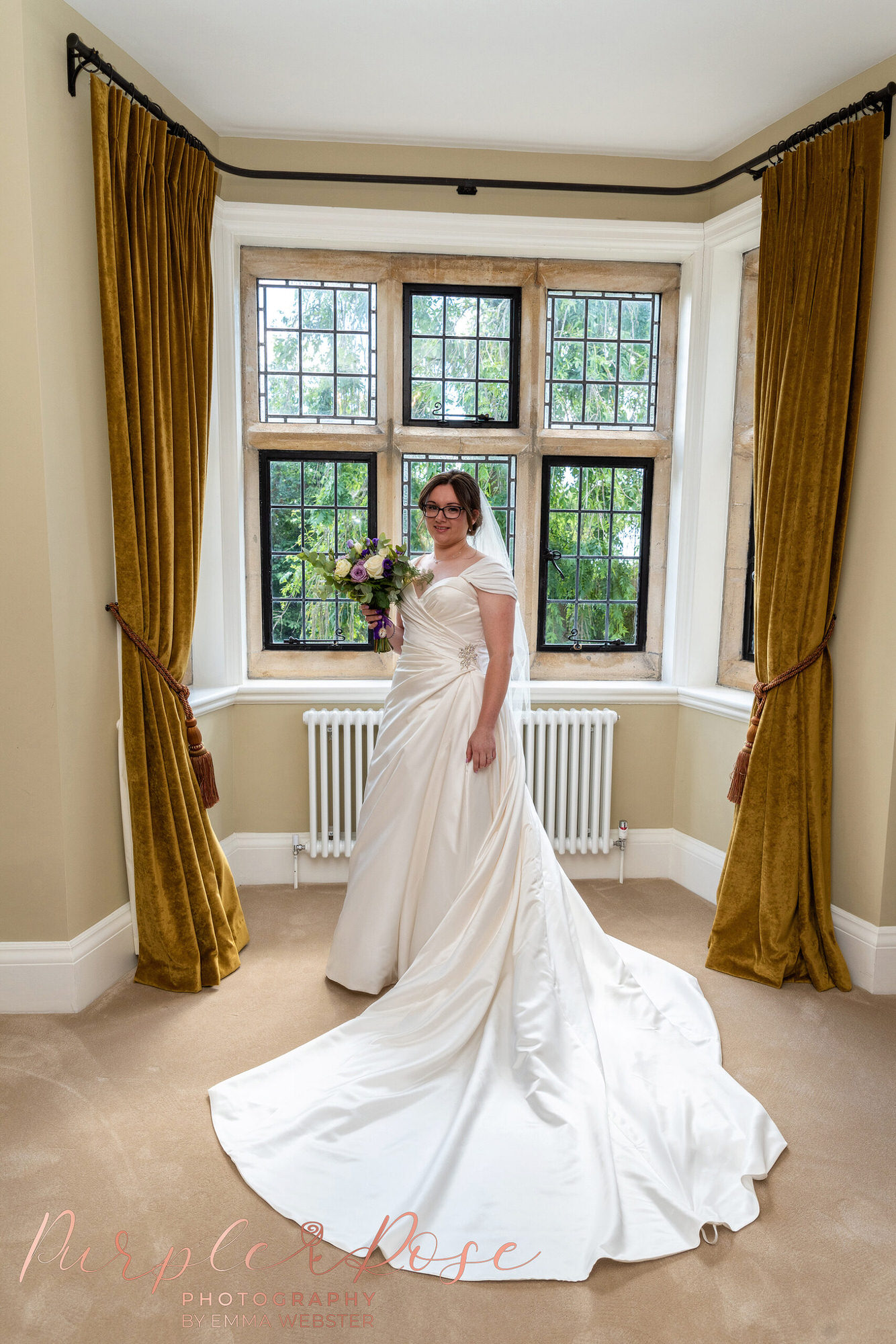 Bride stood in window with her wedding dress fanned out