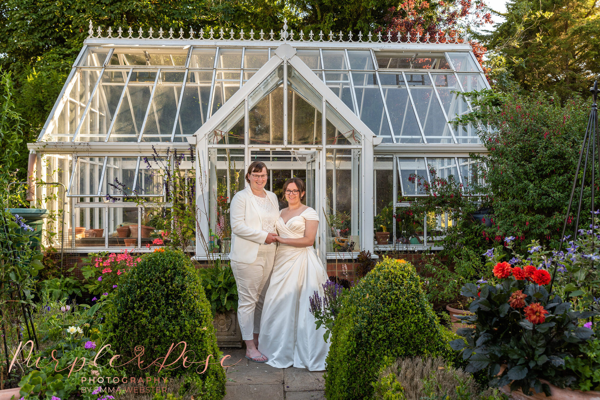 Brides stood in front of a green house