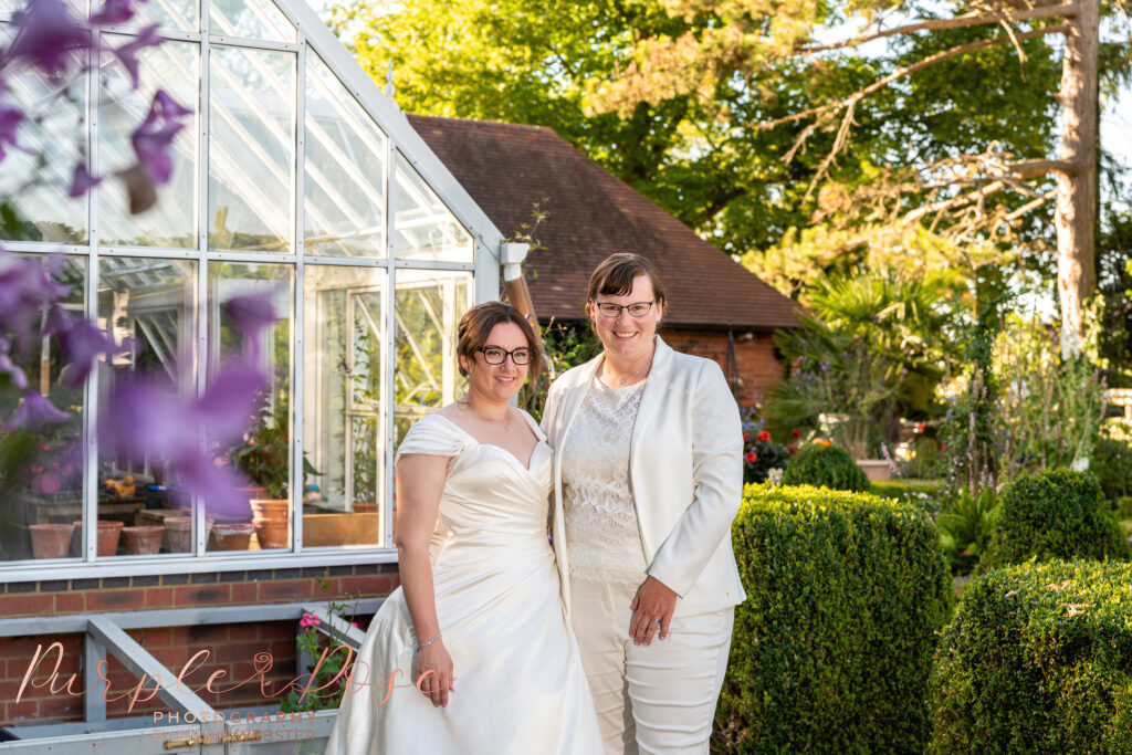 Brides by a green house on their wedding day at Plum Park Manor in Towcester