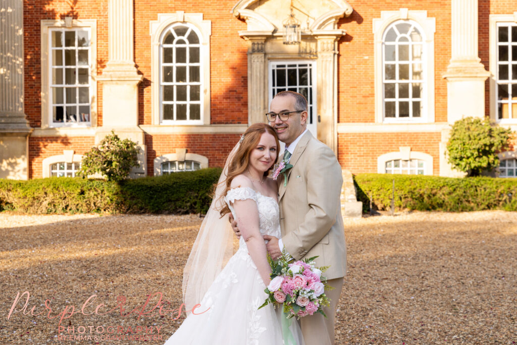 Photo of a bride and groom stood in front of Chicheley Hall on their wedding day in Milton Keynes