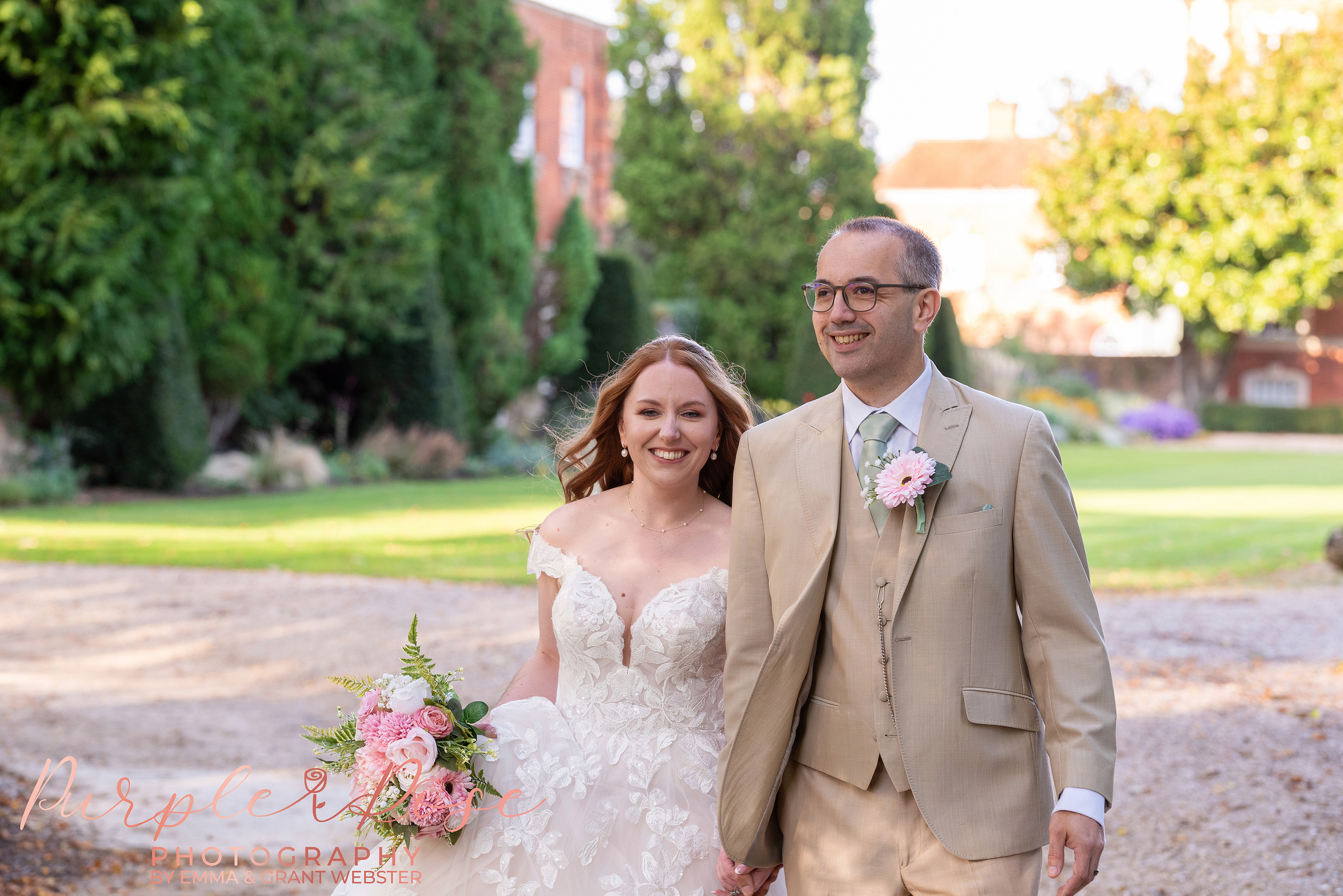 Photo of a bride and groom walking hand in hand along the driveway of Chicheley Hall on their wedding day in Milton Keynes