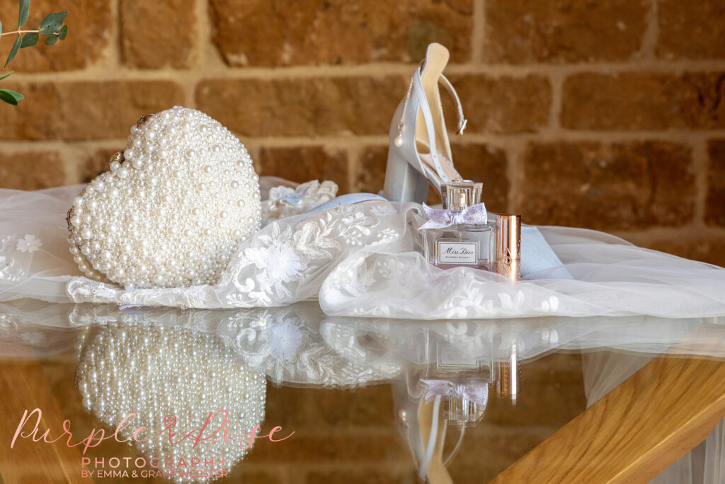 Photo of abrides wedding shoes, bag and other accessories on a table at Dodford Manor in Northampton