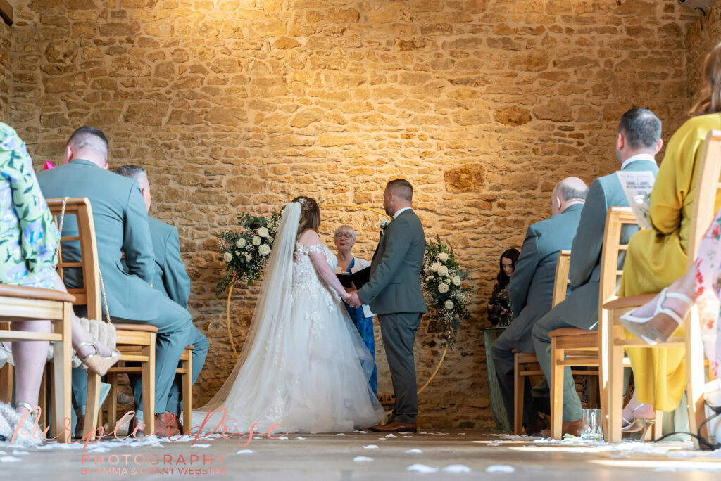 Photo of a bride and groom during their wedding ceremony as they listen to the registrar