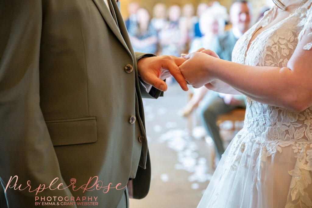 Photo of a bride and grooms hands as they exchange wedding rings during their wedding ceremony at Dodford Manor in Northampton
