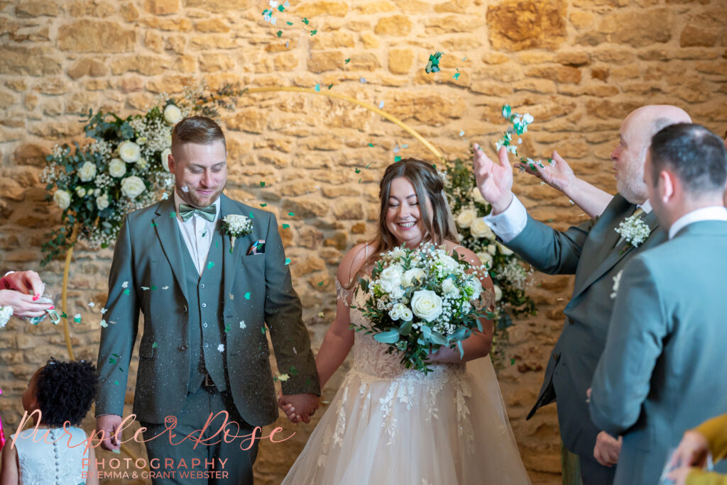 Bride and groom leaving their wedding ceremony as guest throw confetti at their wedding in Northampton
