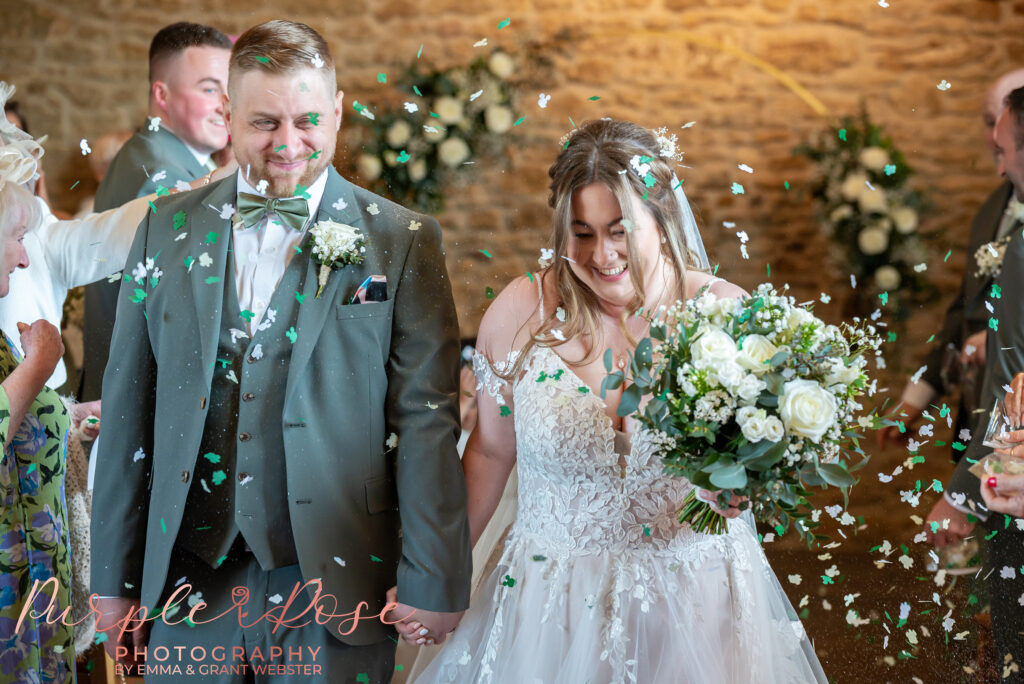 Bride and groom leaving their wedding ceremony as guest throw confetti at their wedding in Northampton