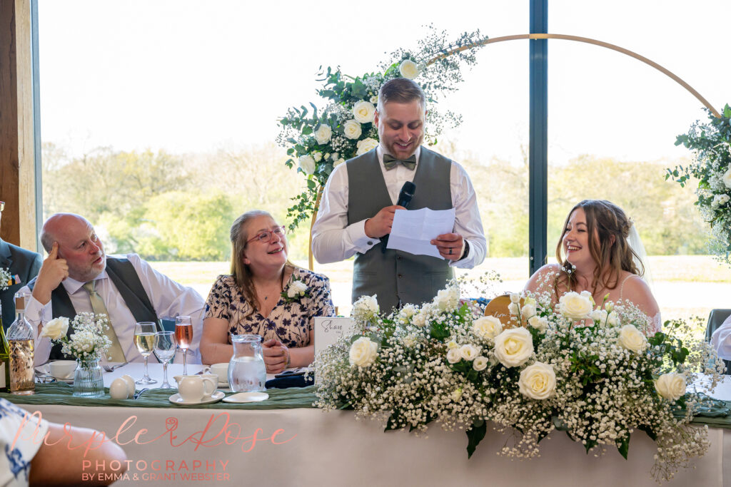 Bride and groom laughing during their wedding speeches at Dodford Manor