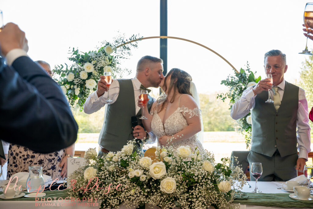 Bride and groom sharing a kiss during their wedding speeches at Dodford Manor