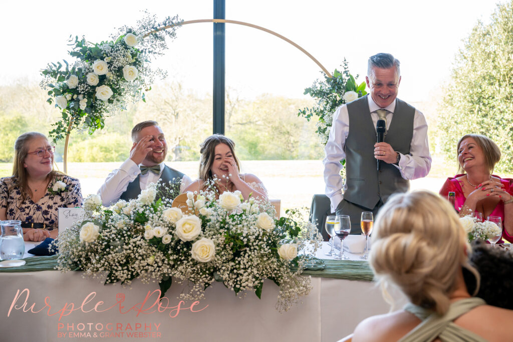 Bride and groom laughing during their wedding speeches at Dodford Manor