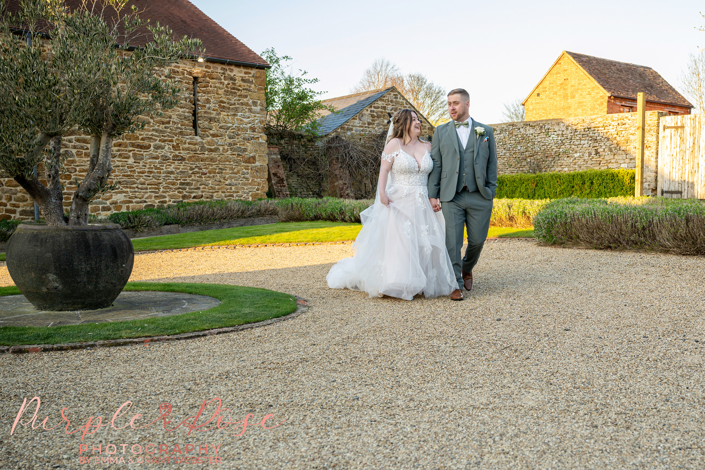 Bride and groom walking hand in hand in the grounds of Dodford manor on their wedding day