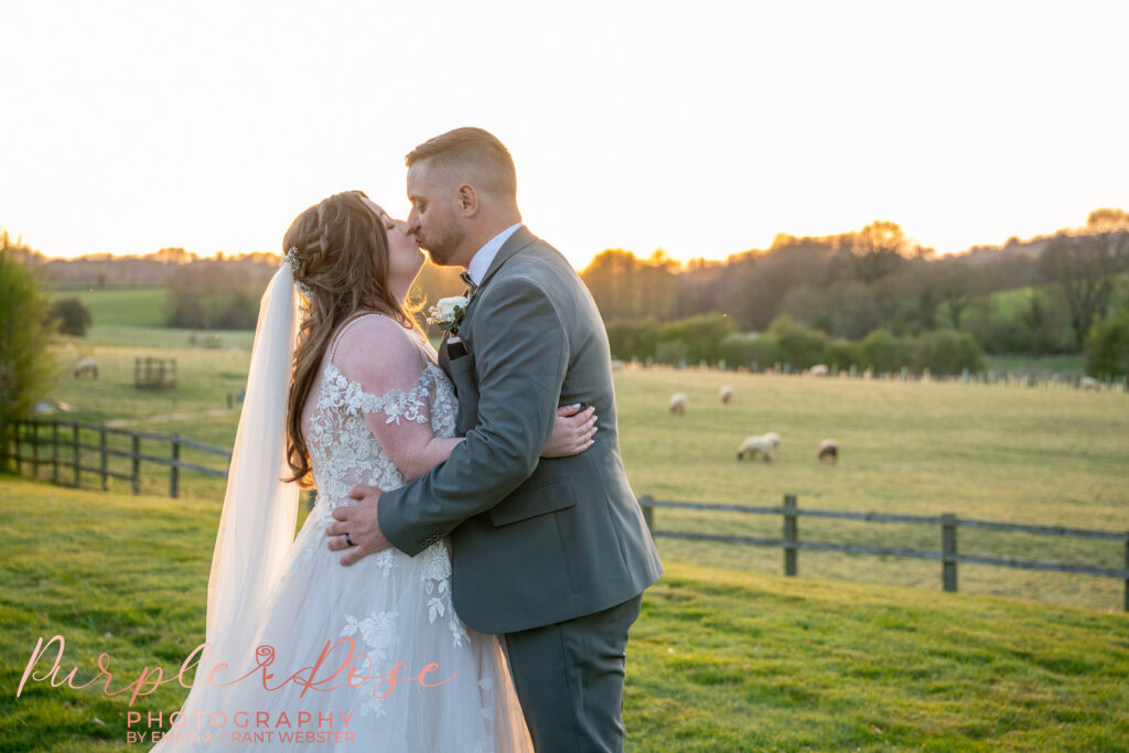 Bride and groom holding hands on their wedding day in Milton Keynes, stood outside with fields behind them.
