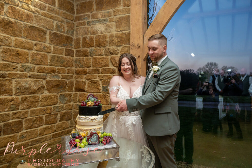 Bride and groom cutting a cheese tower on their wedding day at Dodford Manor