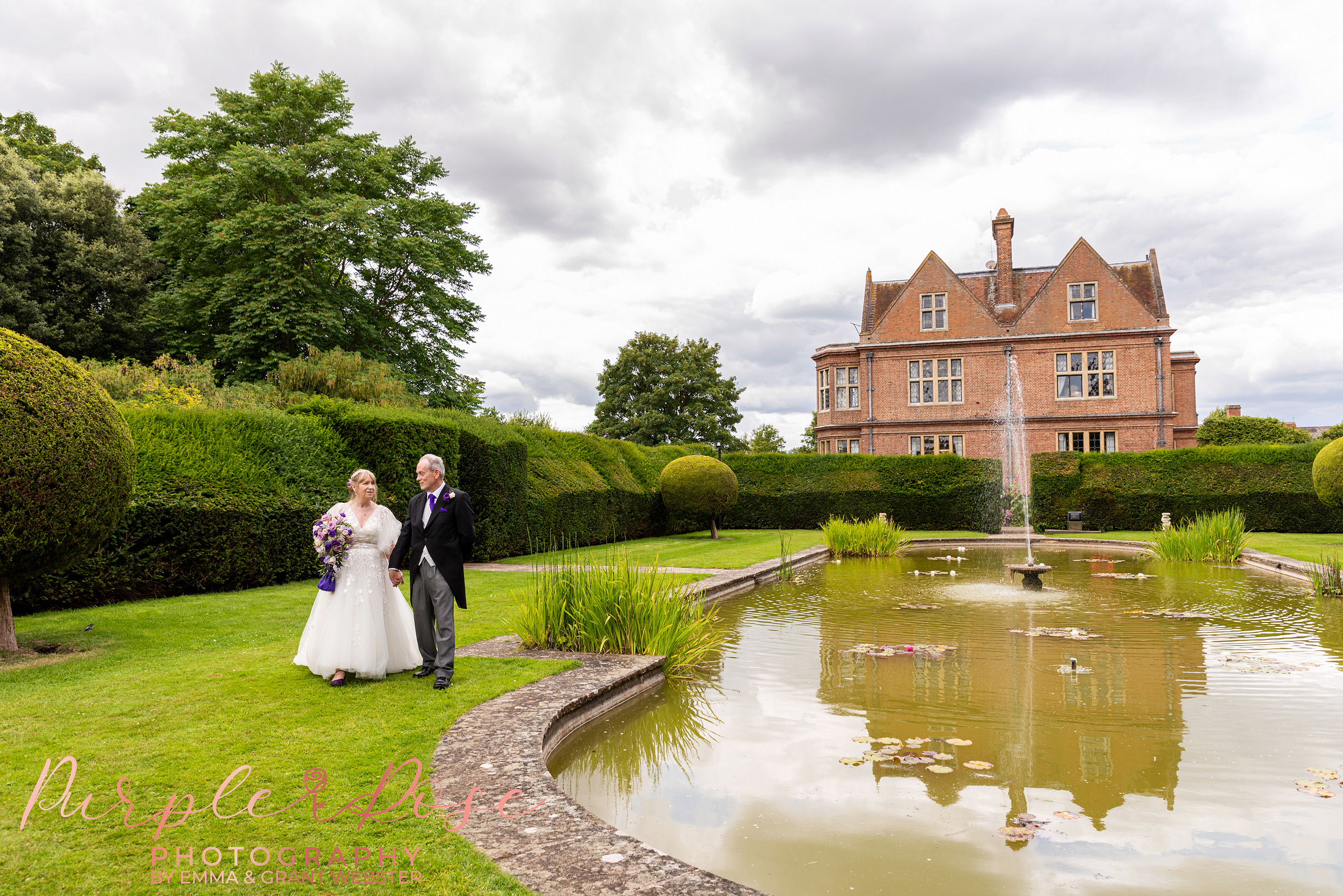 Photo of a bride and groom walking beside a pond on their wedding day in Milton Keynes