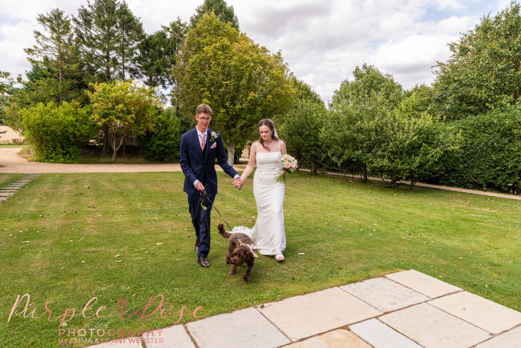 Photo of a bride and groom walking their dog on their wedding day in Bicester