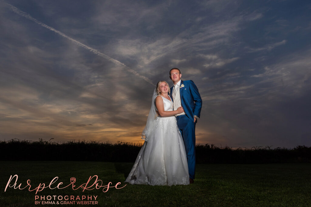 Photo of a bride and groom in a field behind their wedding venue on their wedding day in Buckinghamshire during sunset.