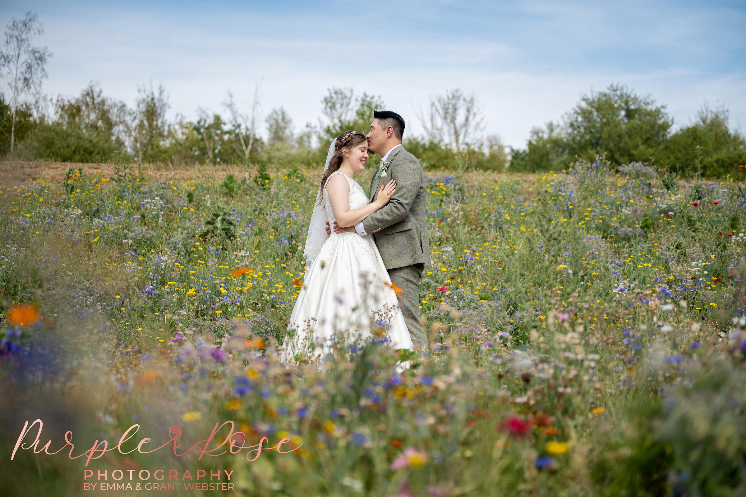 Bride and groom stood in wild flower meadow on their wedding day in Milton Keynes