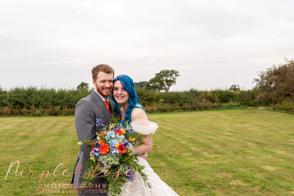 Photo of bride and groom smiling while holding the brides bouquet on their wedding day in Milton Keynes