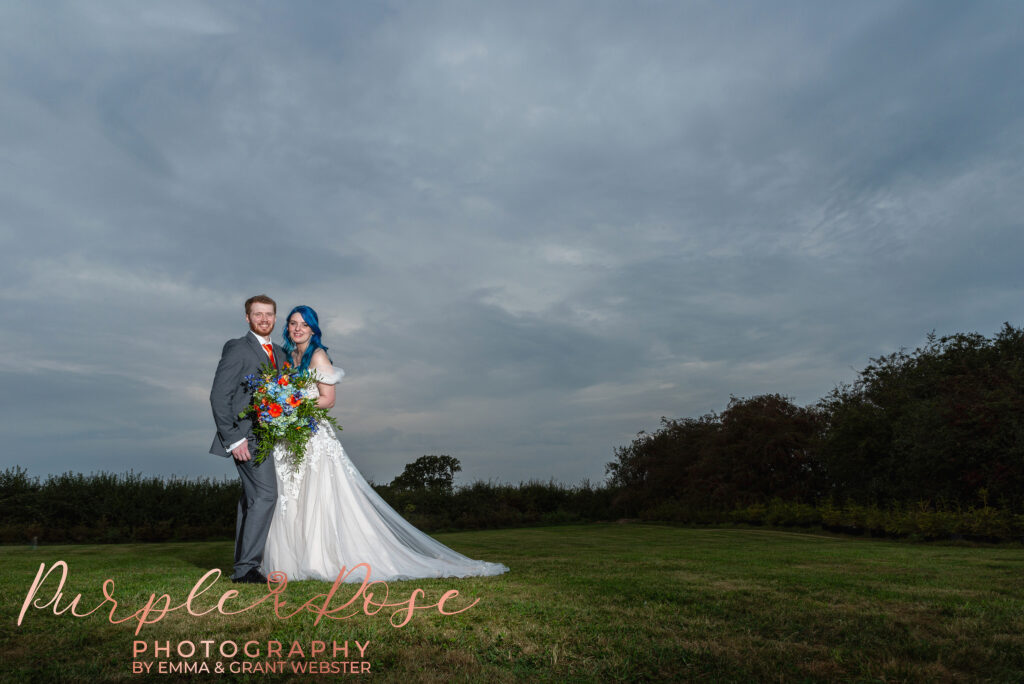 Photo of bride and groom in front of a stormy sky on their weding day in Milton Keynes