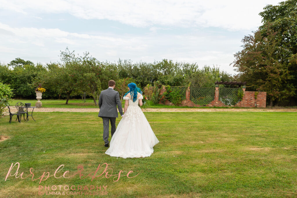 Photo of bride and groom walking away form the camera hand in hand on their wedding day in Milton Keynes