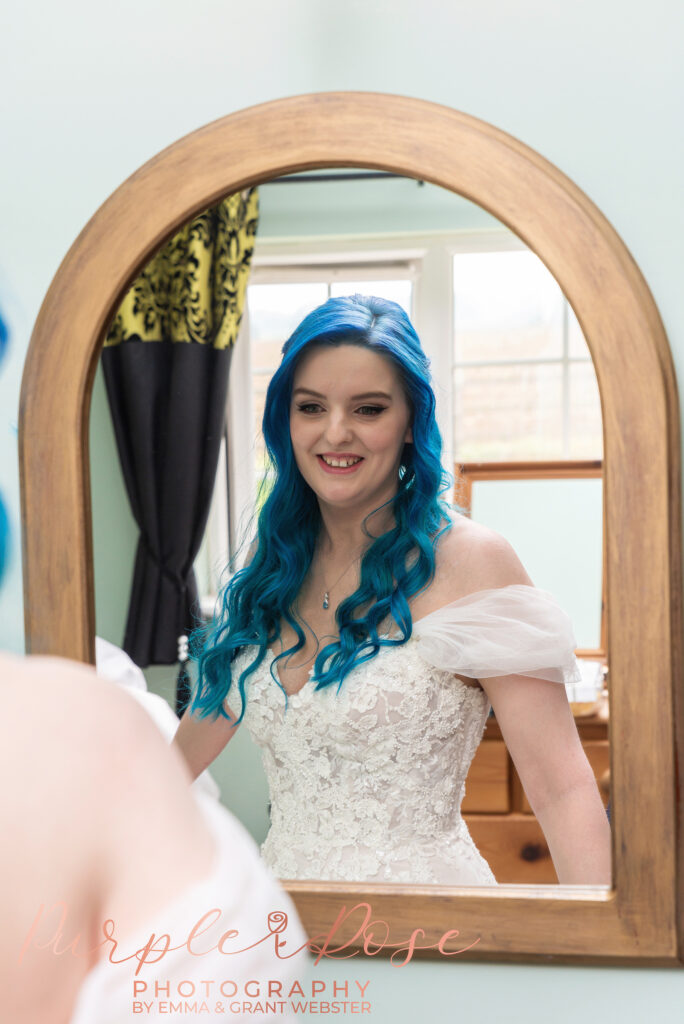 Photo of a bride with blue hair looking in the mirror on her wedding day in Milton Keynes