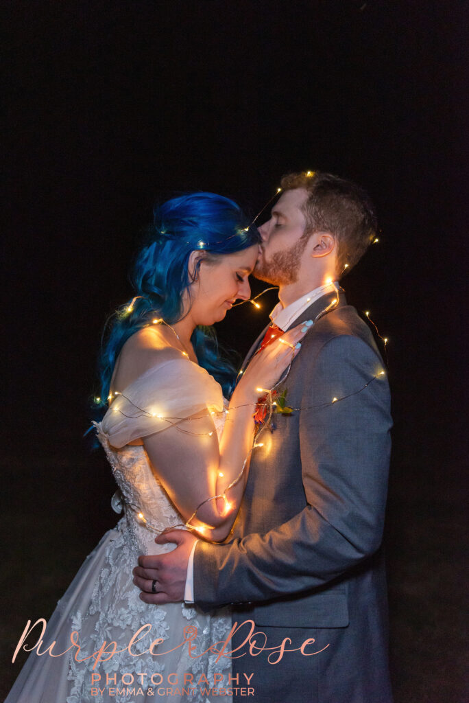 Phot of abride and groom at night wrapped in fairy lights on their wedding day in MIlton Keynes