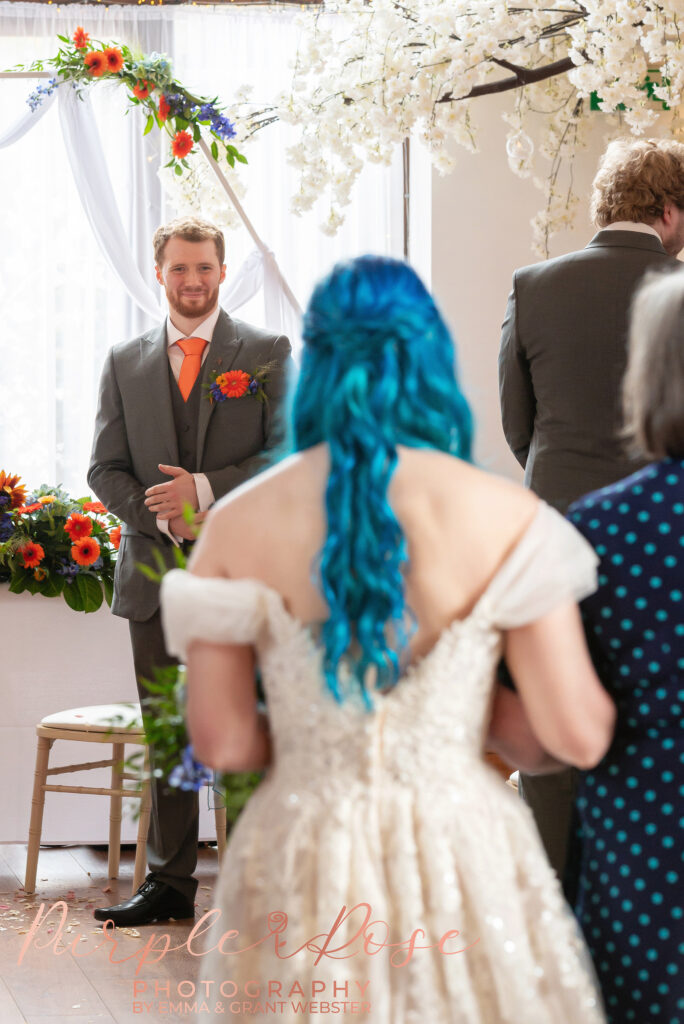 Photo of groom smiling as he see's his bride for the first time on their wedding day in Milton Keynes