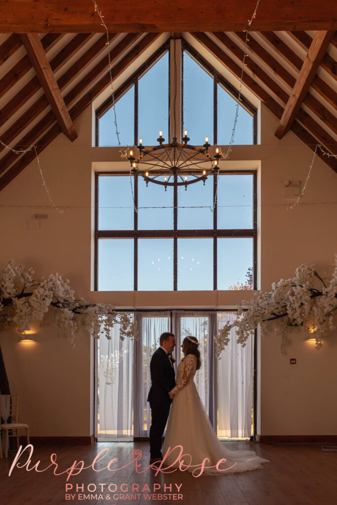 Photo of a bride and groom stood in fornt of floor to ceing windown on their wedding day in Milton Keynes