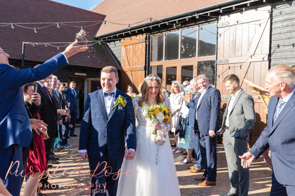 Photo of a bride and groomw laking through confetti on theri wedding day in Milton Keynes