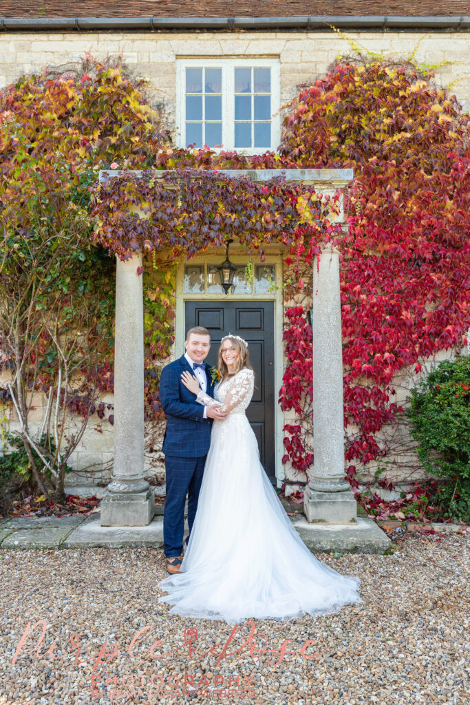 Photo of a birde and groom in fornt of a doorway on their wedding day in Milton Keynes