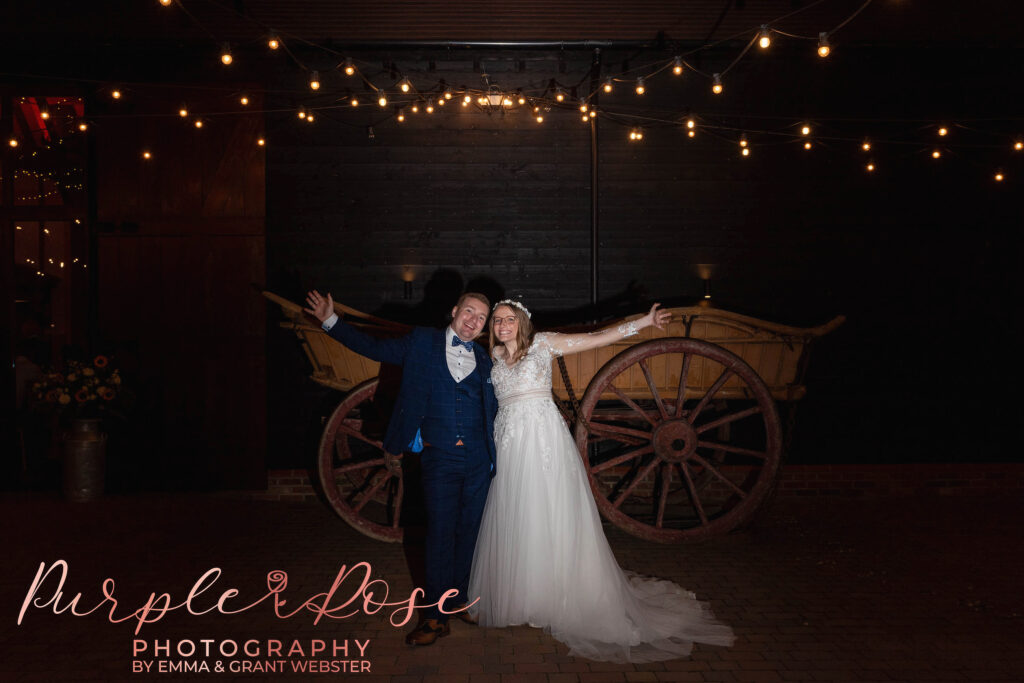 Photo of a bride and groom at night waving on their wedding day in Milton Keynes