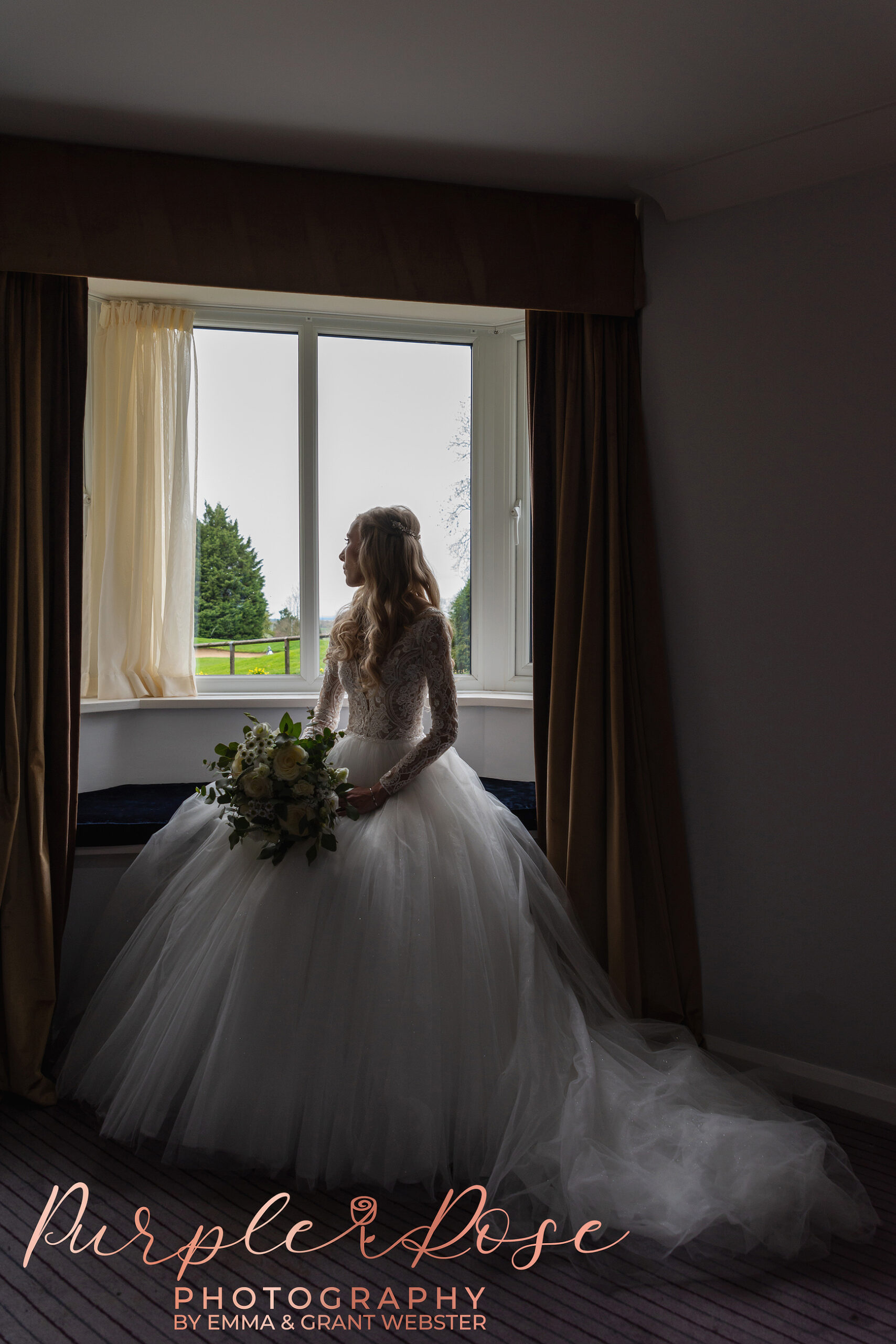 Back lit photo of a bride sat by a window on her wedding day in MIlton Keynes