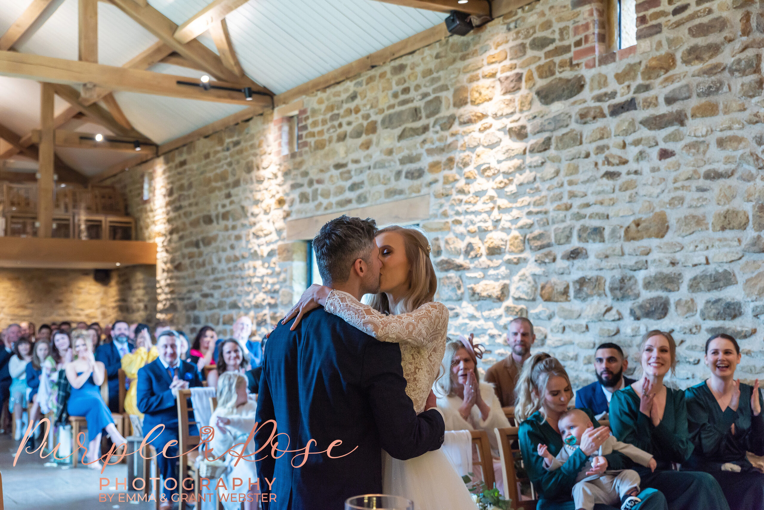 Phot o f bride and groom sharing their first kiss at the end of their wedidng ceremony in Milton Keynes