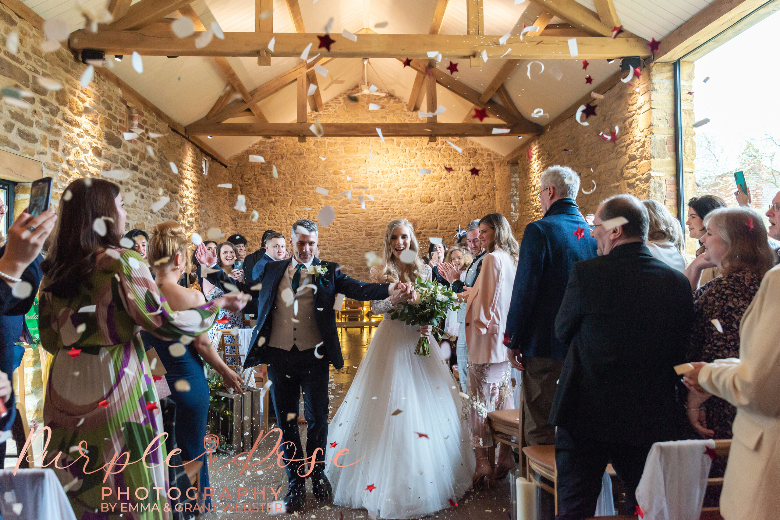 Photo of bride and groom leaving their wedding ceremony as guests throw confetti at ther wedding in Milton Keynes