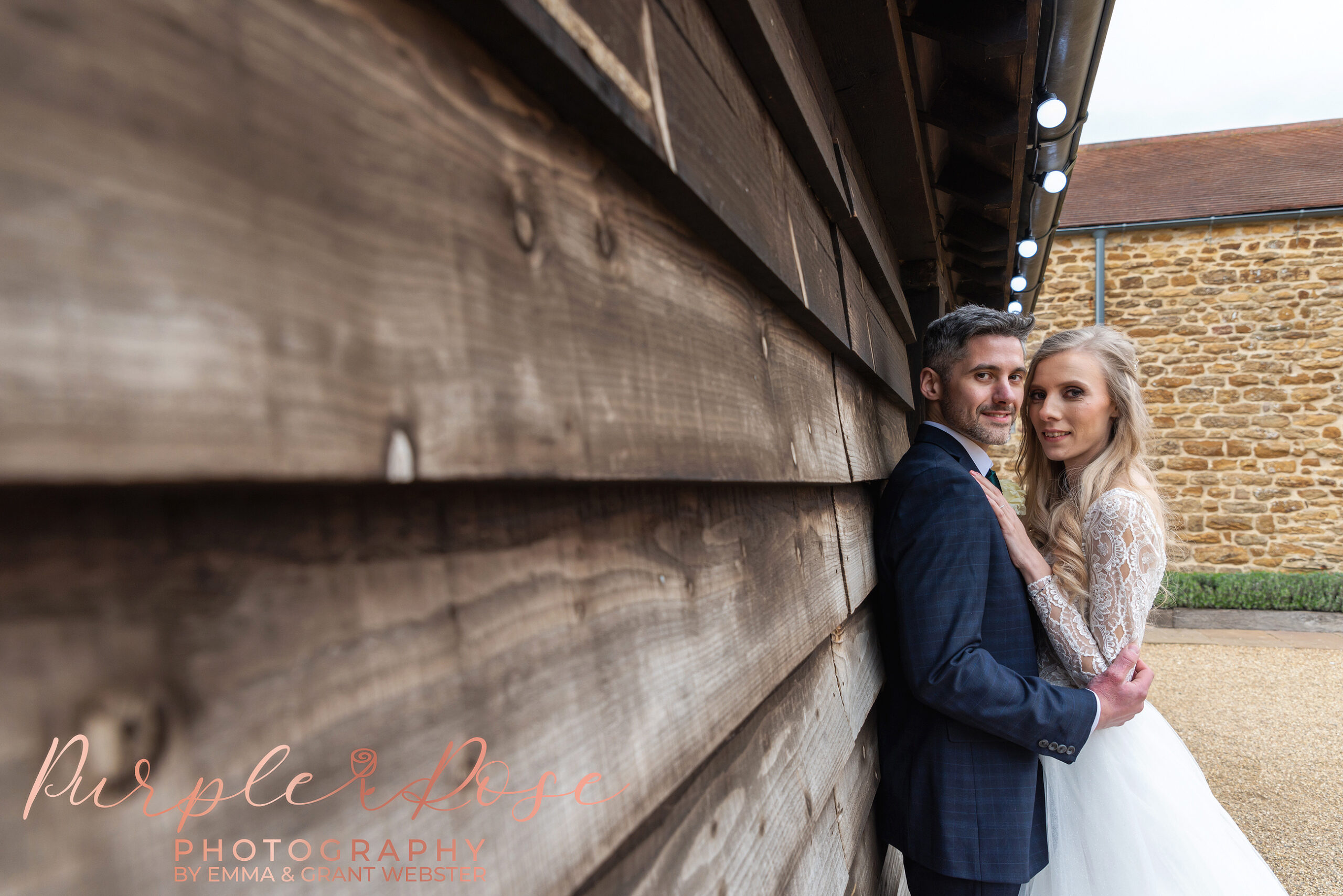 Photo of abride and groom leaning on a barn on their wedding day in MIlton Keynes