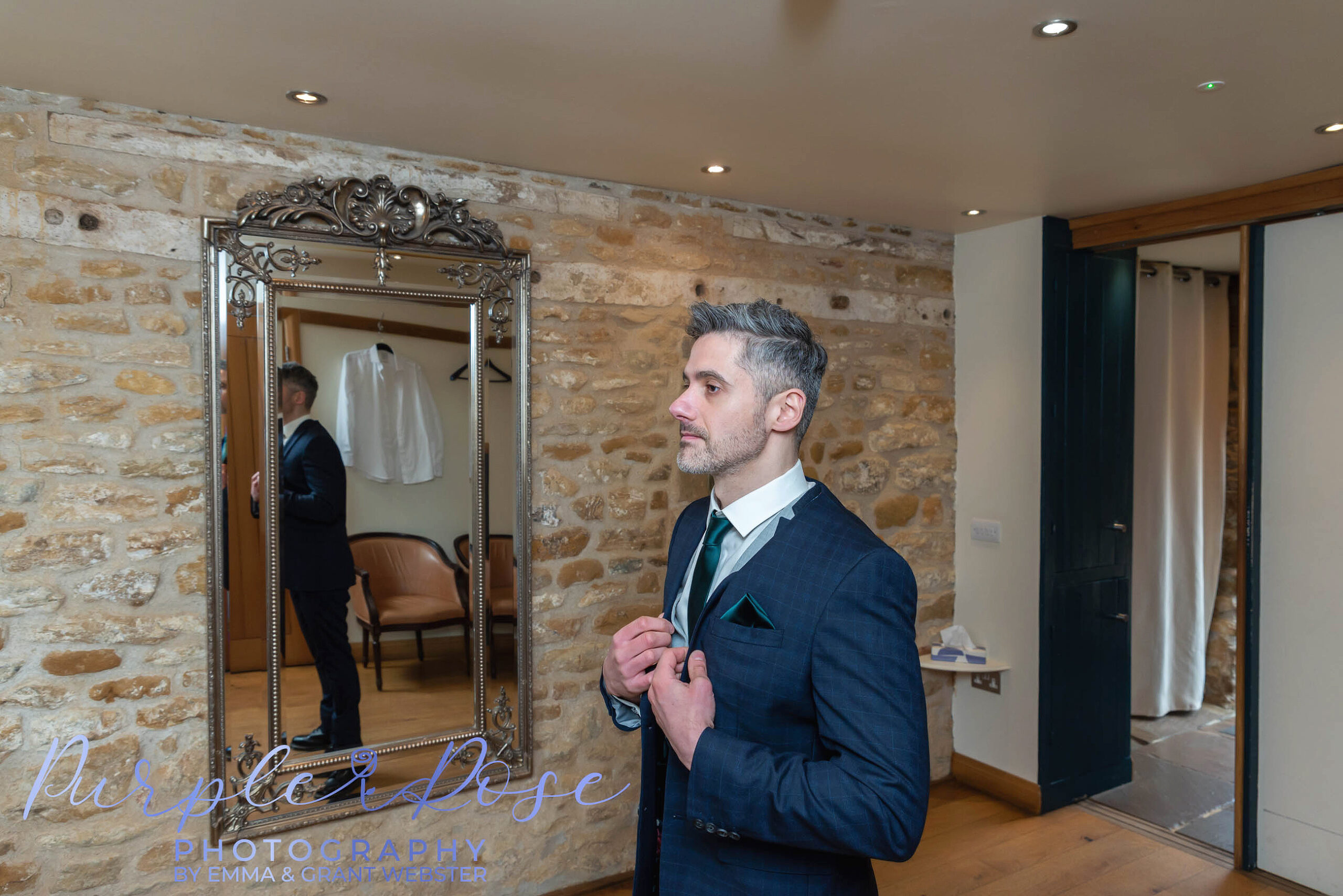 Photo of a groom stood in fornt of the mirror getting ready for his wedding day in Milton Keynes