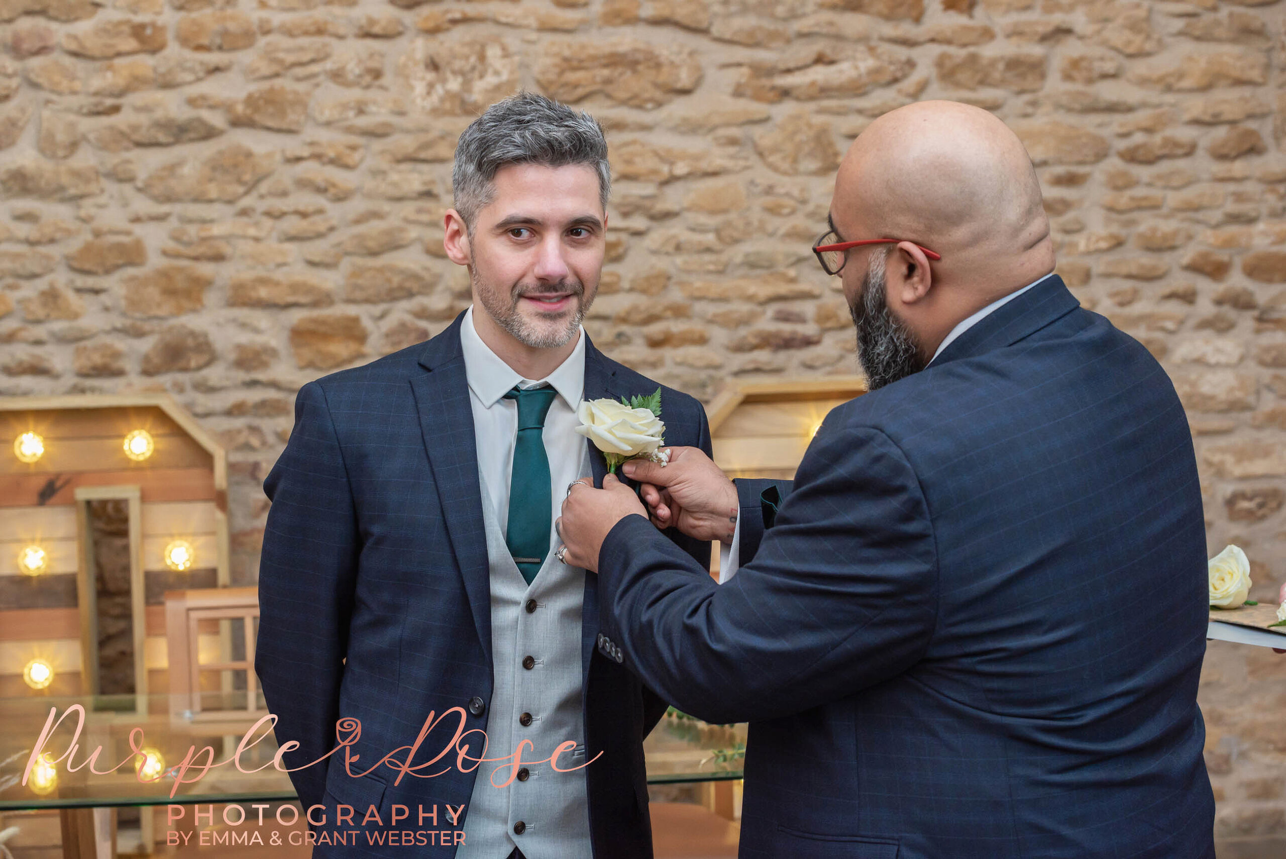 Photo of a groom having his buttonhole adjusted by his best man on his wedding day in Milton Keynes