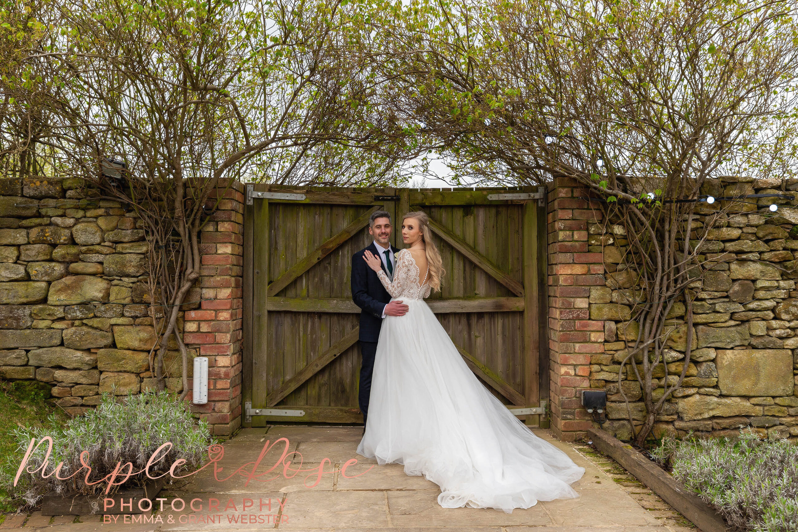 Photo of a bride and groom outside a wooden gate on their wedding day in Milton Keynes